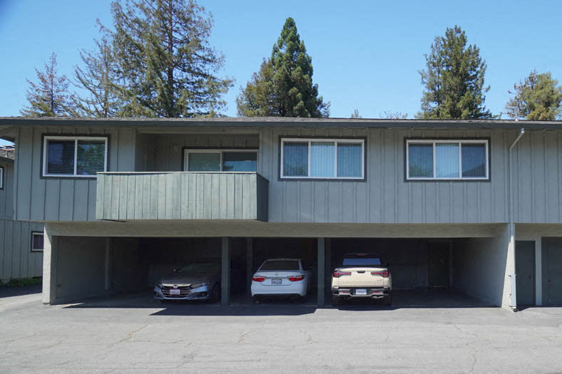 a parking garage with three cars in front of a house